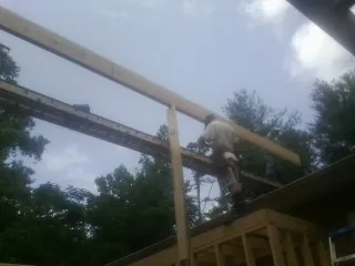 Carpenter setting a ridge beam over a new addition frame — Ice Dam Removal by Roofing Brothers in Bellona