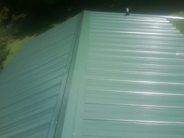 New green metal panels meeting at the ridge of a roof — Flat Roof Repair work by our crew in Bellona