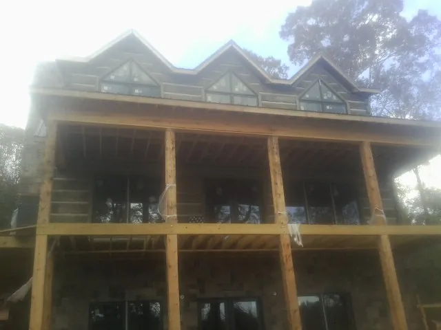 Dormers and porch framing on a large log home under construction — Roof Coating work by our crew in Bellona