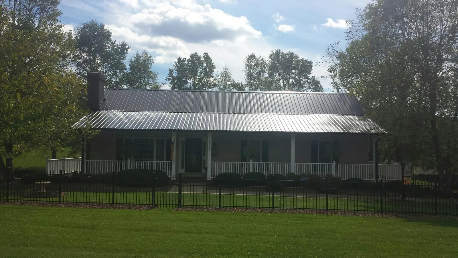 Gray metal roof on a brick ranch with a full width front porch — Gutter Guard Installation work by our crew in Bellona