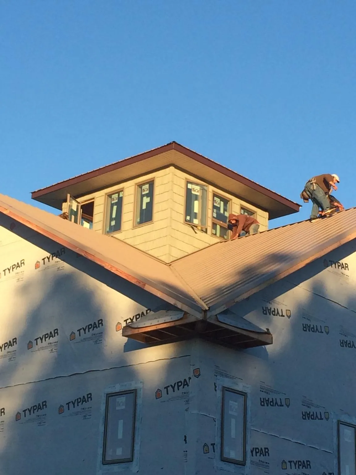 Roofers working around a rooftop cupola on a new metal roof at sunset — Roof Waterproofing in Bellona by Roofing Brothers